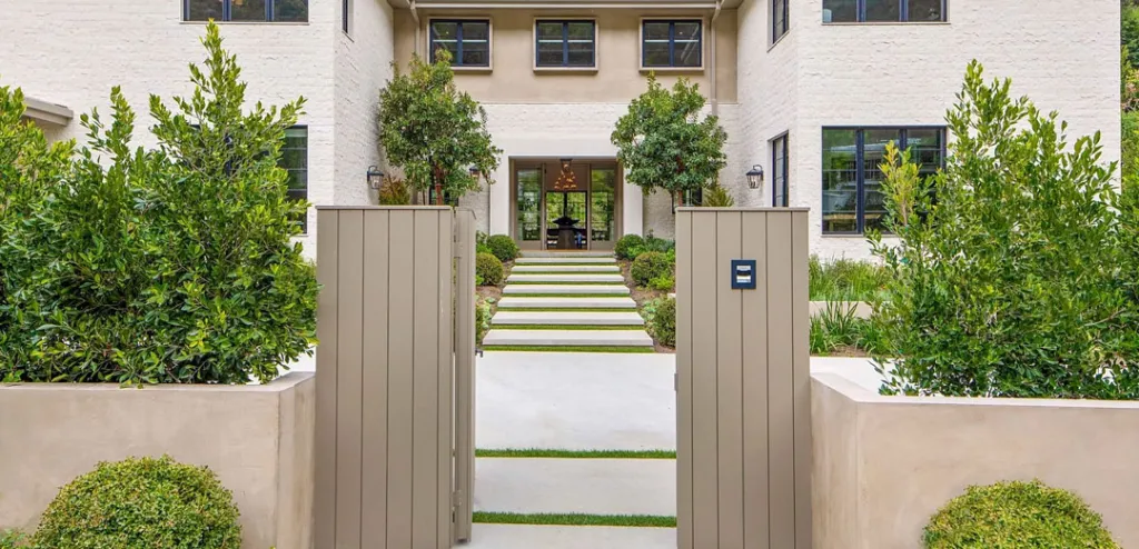 a white brick house with a wooden gate leading to it