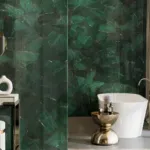 Luxurious bathroom featuring a deep green marble wall, white freestanding tub, gold table, and modern vanity.