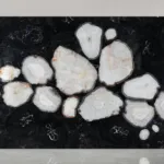 Cluster of irregular white shapes resembling stones or crystals set against a dark black background.