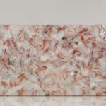 Polished pink marble slab with intricate white and red flecks against a plain background, conveying elegance.