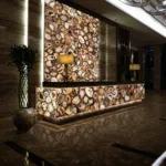 Luxurious hotel lobby featuring a backlit marble reception desk with circular patterns, warm lighting, and elegant decor.