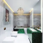 Luxurious bathroom with elegant marble walls, green marble sink and bathtub, gold fixtures, and a crystal chandelier.