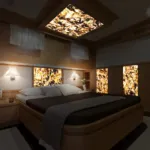 Luxurious bedroom featuring illuminated stone wall and ceiling panels, warm lighting, soft bedding, and modern decor.