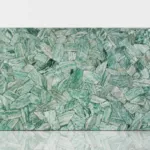 Polished stone slab featuring a reflective mosaic of green stones in varying shades.