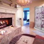 Luxurious room featuring a stone fireplace, lit candles, and a vibrant mosaic shower with a purple tree design.