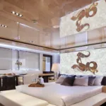 Modern luxury bedroom featuring a large bed with white and gray pillows, elegant lamps, and a marble art accent wall.