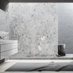 Modern bathroom featuring a white floating vanity, large marble-textured wall, and a lush green plant.