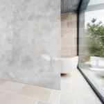 Modern bathroom featuring a large marble shower wall, stone tiles, and a freestanding tub by a floor-to-ceiling window.