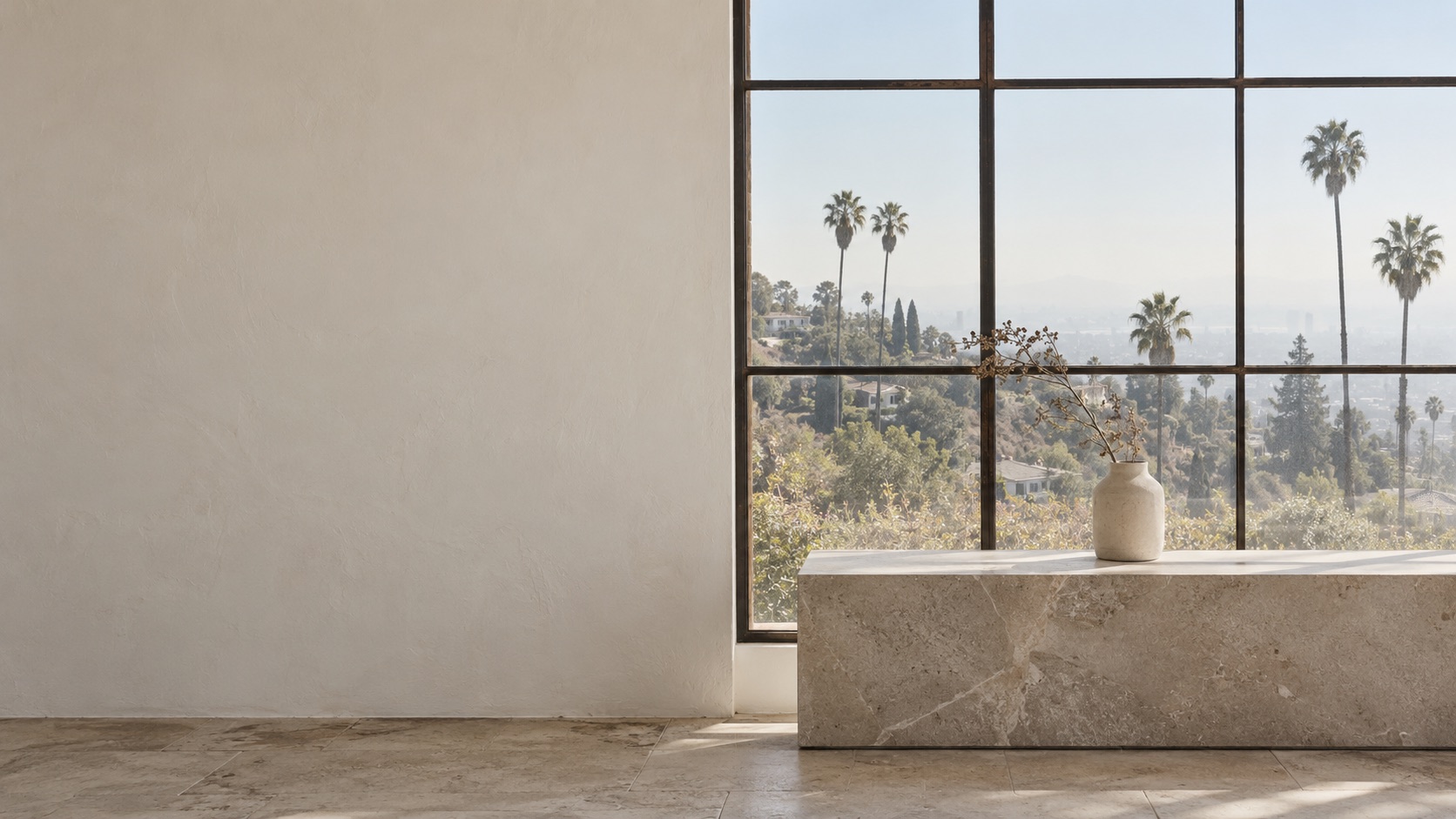 Honed stone bench by a steel window overlooking the Los Angeles hills and palm trees